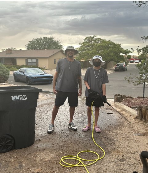 The Johnson Boys crew, dad and son, standing with a trash barrel and their pressure washing gear