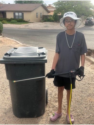 Gloved up with the pressure wand next to a trash barrel